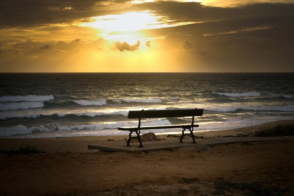 Leere Bank vor dem Hintergrund des Sonnenuntergangs am Meer