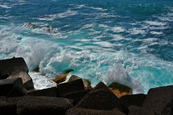 Ocean waves break with foam on coastal rocks