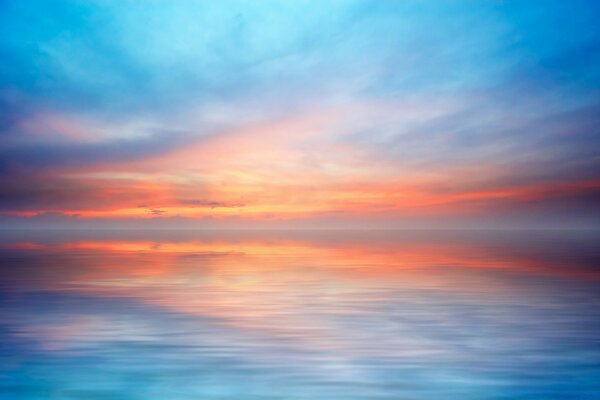 Ruhiges Meer bei Sonnenuntergang am Sommertag, die letzten Sonnenstrahlen erhellen den Himmel über dem Wasser