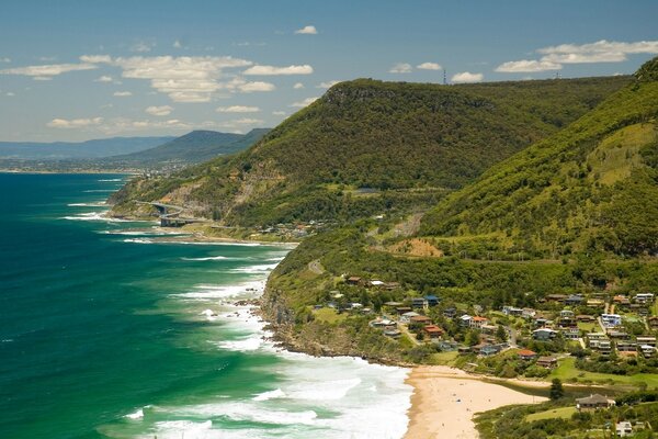 The coast with houses on the background of the sea and green hills