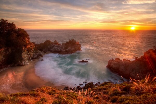 Una bahía en el océano con vistas a una colorida puesta de sol