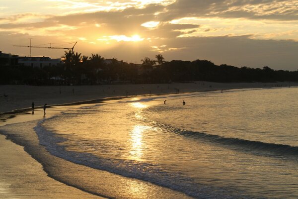 Coucher de soleil sur une plage tropicale, les vagues de la mer légère se précipitent sur le sable