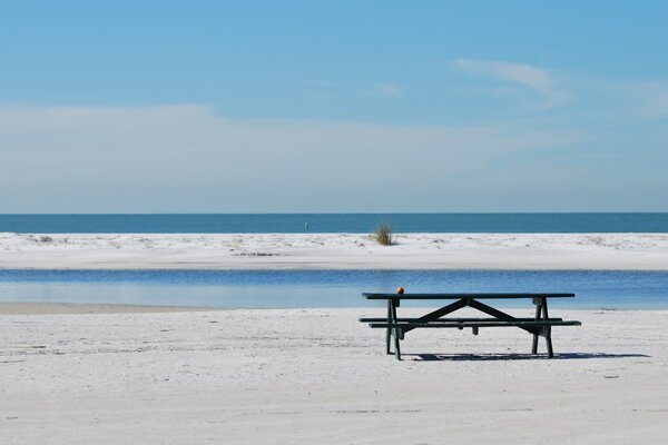 Eine Bank am Sandstrand vor dem Hintergrund der Wellen