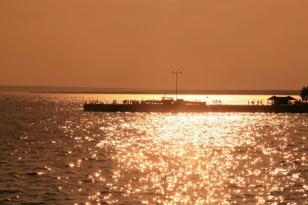 Coucher de soleil au bord de la mer dans les tons orange, jetée