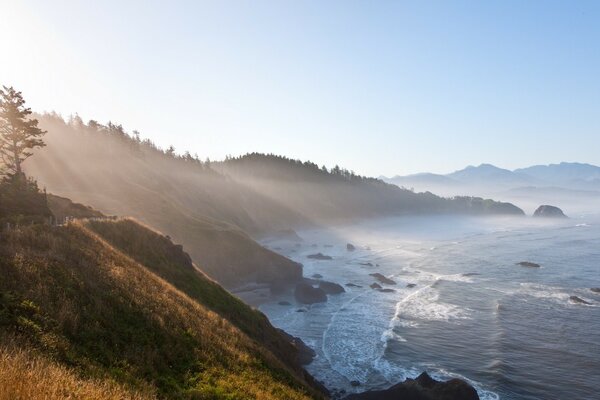 Las olas golpean las rocas en los rayos del amanecer