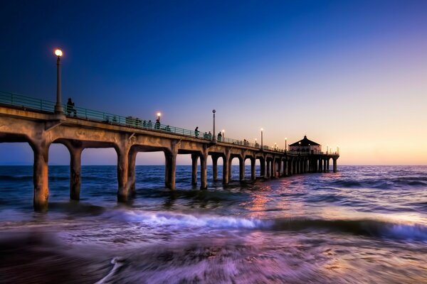 Pier and restless sea on sunset background