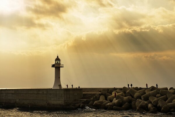 Farol no fundo do sol poente escondido das nuvens