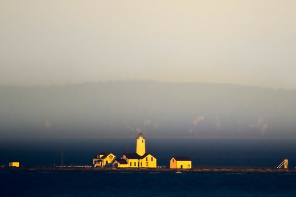 Phare et maisons sur un îlot au milieu de l océan