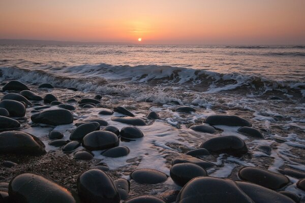 Sunset in the ocean and big rocks on the shore