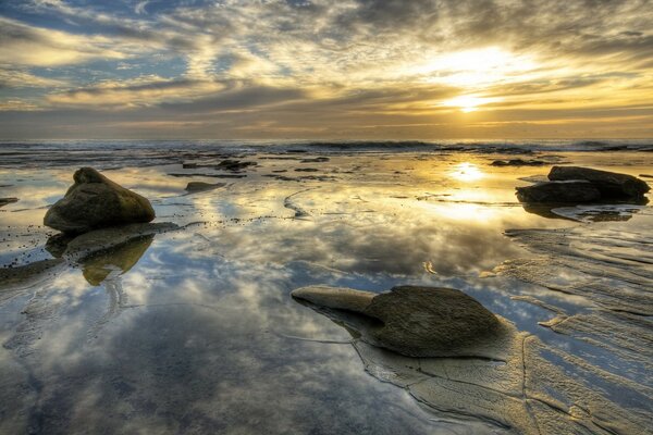 Puesta de sol en el mar con piedras afiladas fuera del agua