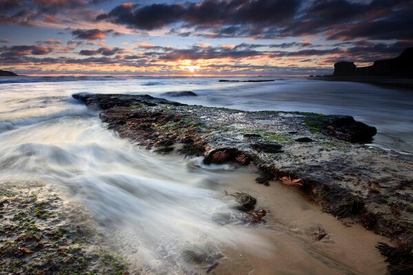 Not calm sea water washes the rocky beach