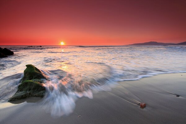 Plage de mer avec des vagues sur fond de coucher de soleil