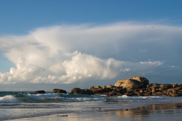 Wellen am Sandstrand vor dem Hintergrund der Wolken