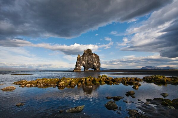 Huge stones stick out of the sea water, which reflects the sky