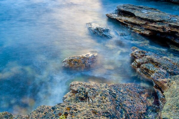 Océano transparente con rocas en la niebla