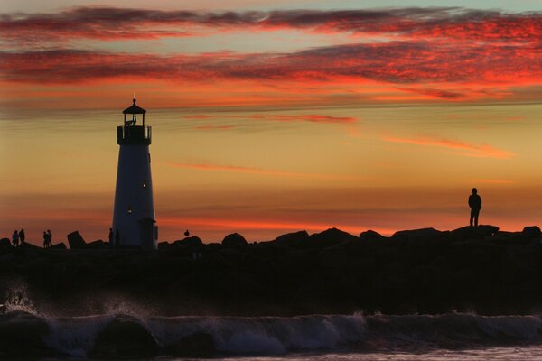 Silhouette of a man and a lighthouse against the sky