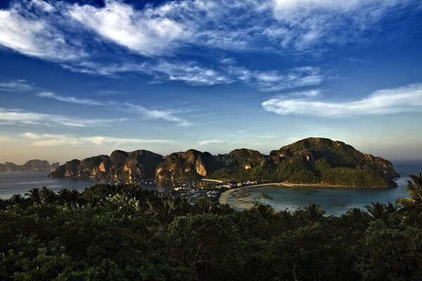 Beautiful landscape with mountains and green trees on both sides of the sea at sunset