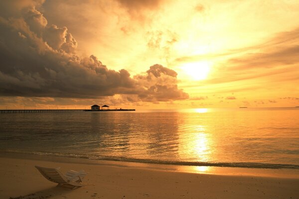 Atmosférica praia com espreguiçadeira e oceano ao pôr do sol