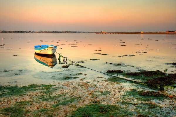 Puesta de sol y barco que se refleja en el océano