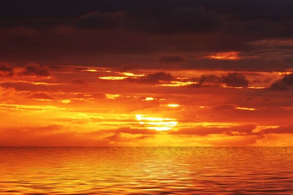 Crimson sunset through the clouds over the ocean