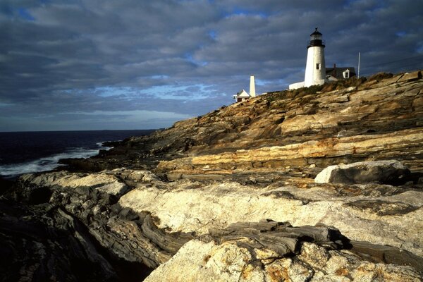 Phare sur la montagne et le ciel nuageux au-dessus de la mer 