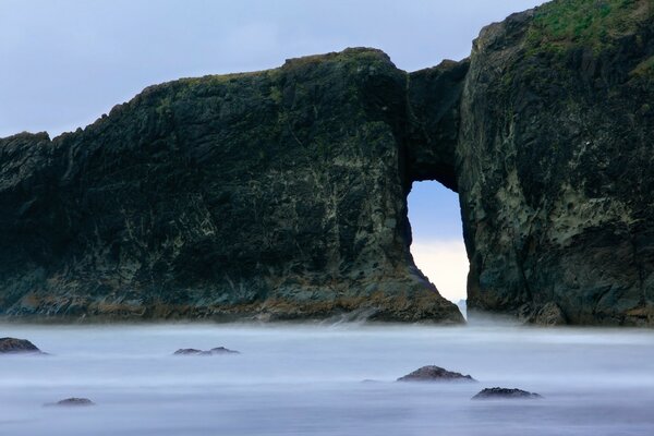 Rocky bridge in the foggy ocean