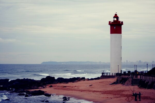 Ein einsamer weiß-roter Leuchtturm am Meer