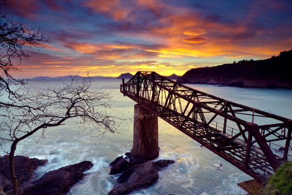 Pont sur la mer. Coucher de soleil et montagnes