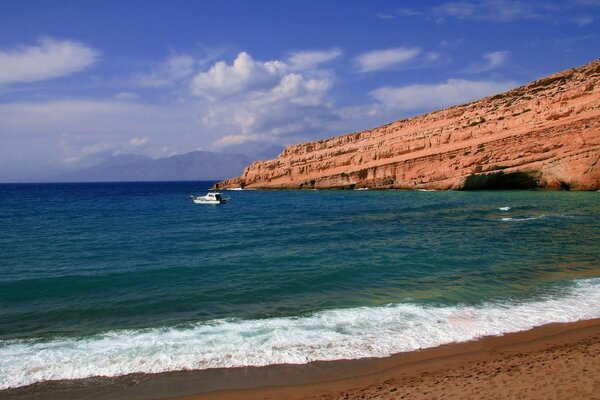 Mar azul e céu, praia e caverna na rocha