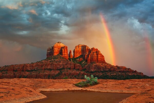 Arco iris en el cielo y puesta de sol en el desierto