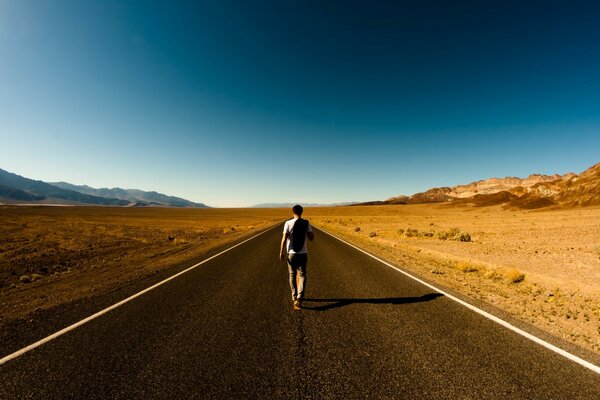 Um homem caminha sozinho por uma estrada deserta