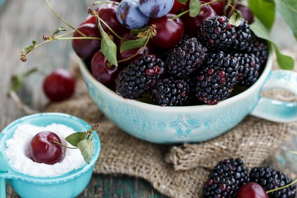 Mulberry in a blue cup. Berries in bright dishes