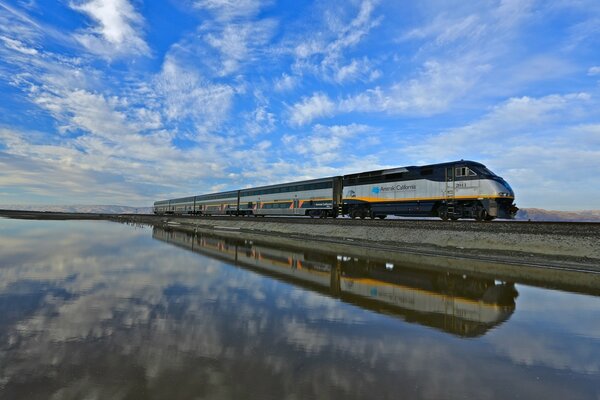 Entre dos mundos sin fronteras (imagen de espejo de un tren bajo un cielo azul)