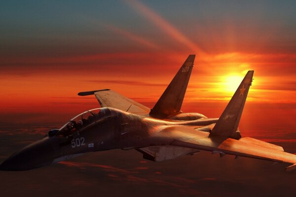 A fighter jet flies against the background of sunset