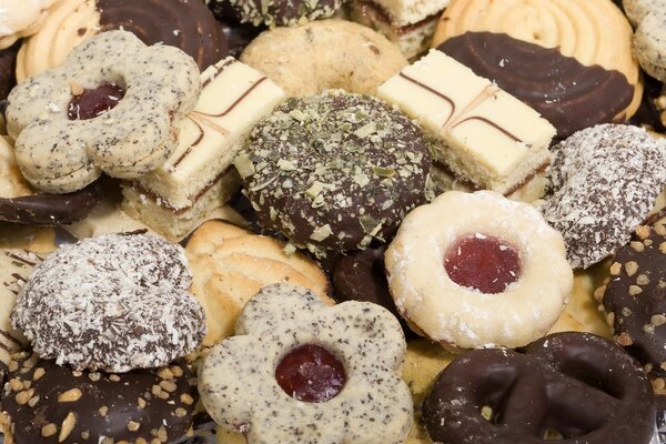 Biscuits assortis, au chocolat blanc et noir, saupoudrés de noix avec l ajout de confiture. En forme de fleurs et de bretzels