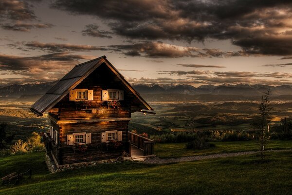 Wooden house in a field against a cloudy , evening sky