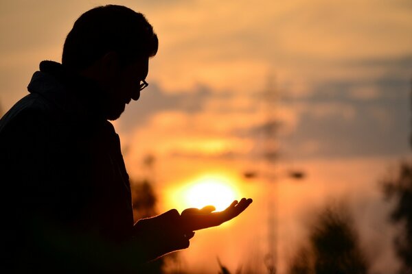 Die untergehende Sonne auf der Handfläche eines Menschen