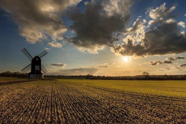 Wolken und Sonne über der Mühle im Feld