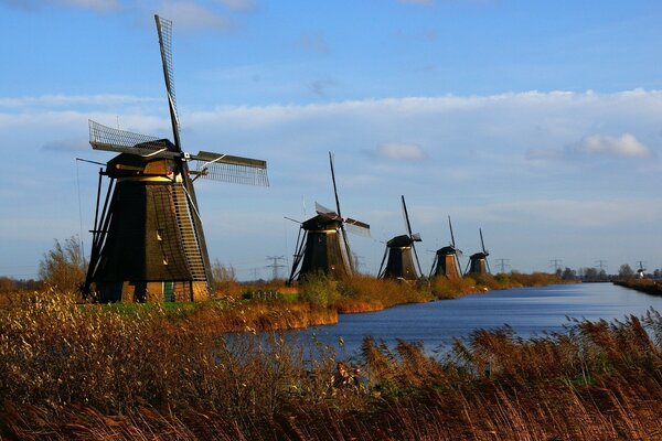 Windmühlen entlang des Flusses in einer Herbstlandschaft