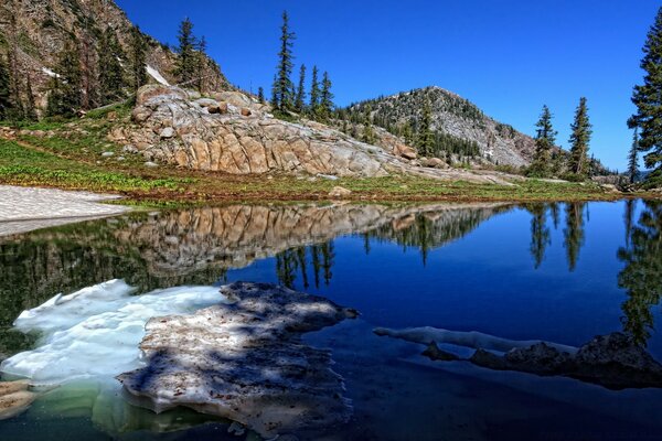 Transparent mountain lake on the background of stone rocks and trees