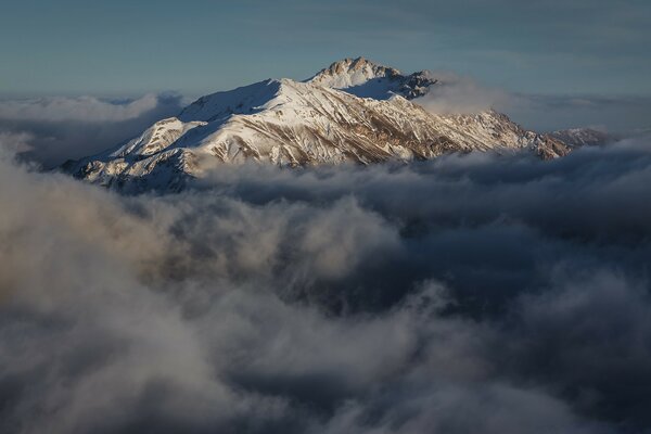 Wolken, die schneebedeckte Berge umhüllen