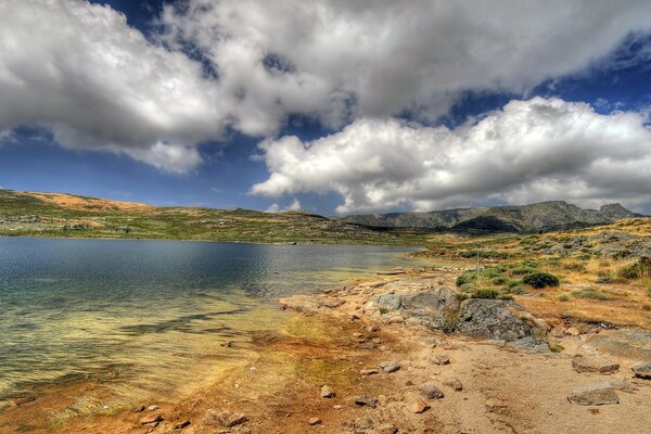 Landscape of a hilly area with a lake under the sky