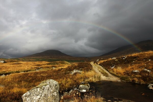 Berglandschaft mit finsterem Himmel und Regenbogen