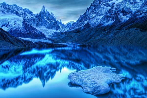 नीले टन में एक झील के साथ एक पर्वत श्रृंखला