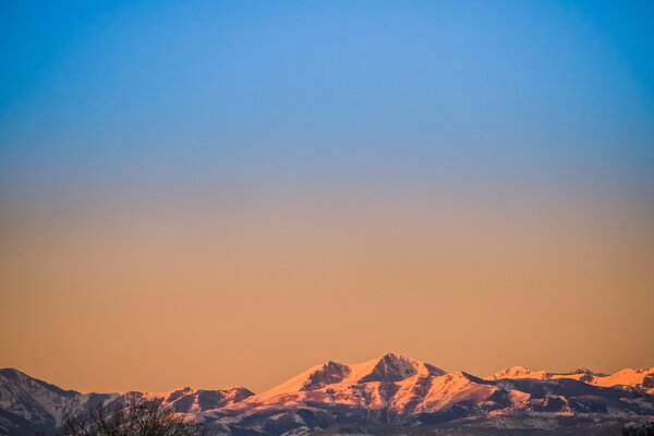 Amanhecer laranja além das altas montanhas