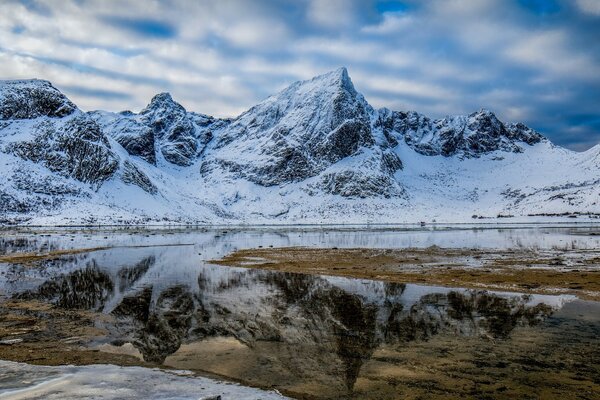 Snow-capped mountains are reflected in the water of the lake