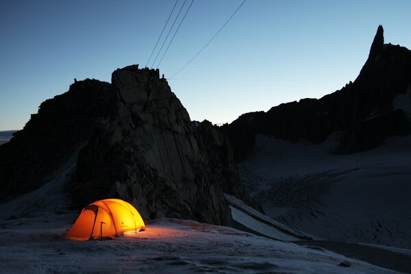 Tente avec lanterne au crépuscule dans les montagnes