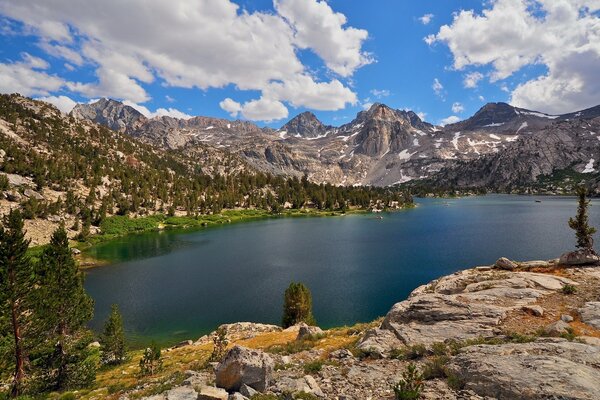 Landscape. Lake in the mountains, clouds in the sky and snowy peaks