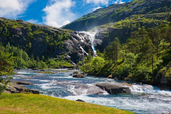 El río fluye cerca de las altas montañas