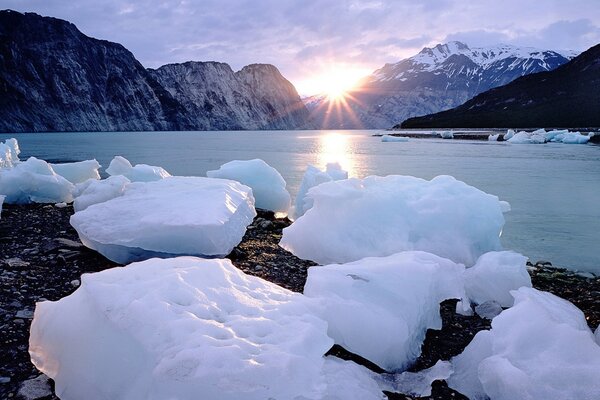 Eisblöcke im Sonnenlicht vor dem Hintergrund von Bergen und Wasser